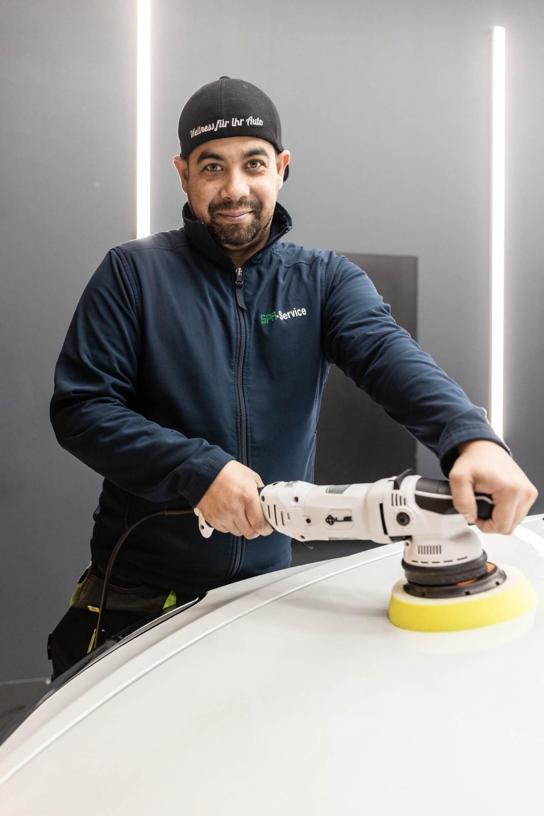 Ein Mitarbeiter, der den weissen Lack eines Autos poliert